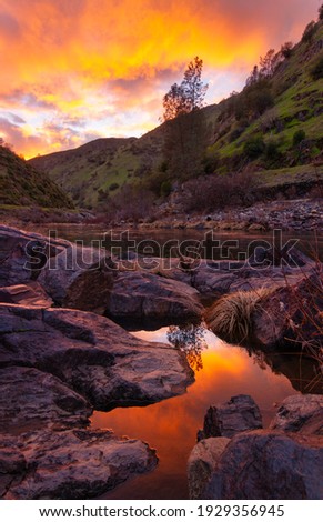 Sunset over the Merced River as it flows into Yosemite National Park.  The brilliant colors are reflected in a small pool next to the river. 