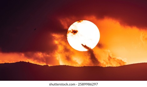 A Sunset over a mountain range with clouds covering it
