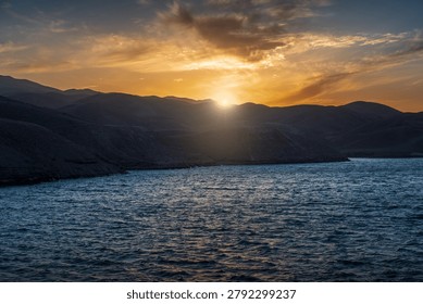 Sunset over mountains reflected on a calm body of water