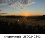 sunset over mountaintops with white clouds overlaying a blue sky