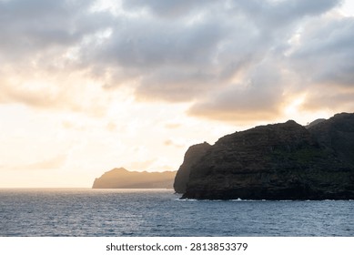 Sunset over the ocean with a distant cliff silhouette off Kauai