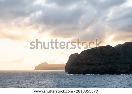 Sunset over the ocean with a distant cliff silhouette off Kauai