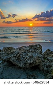 A sunset over the ocean with rocks