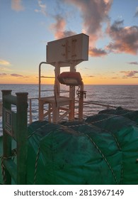 
Sunset Over Ocean from Ship Deck with Safety 
Beautiful sunset over the ocean viewed from ship deck. Maritime safety equipment including lifebuoy and cargo net in foreground with colorful orange sky and calm sea at dusk. Nautical, shipping .