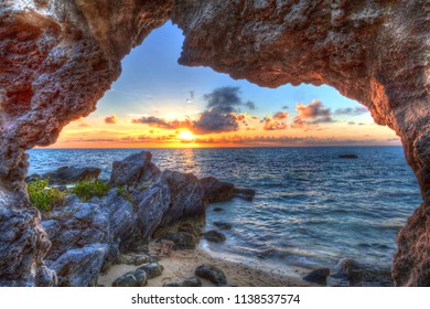 Sunset over the ocean viewed through a natural arch rock formation.