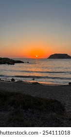 Sunset Over Open Ocean with Waves on Beach and Distant Island