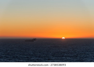 Sunset over the Pacific Ocean with distant ship silhouettes on the horizon.