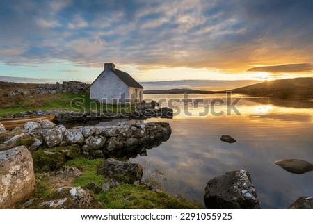 Sunset over a pretty cottage on the shores of a lake at Screebe in the Connemara national park in County Galway in Ireland