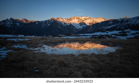 Sunset over the Pyrenees mountains with the reflection of the peaks in the water of the lake