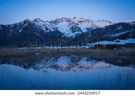 Sunset over the Pyrenees mountains with the reflection of the peaks in the water of the lake