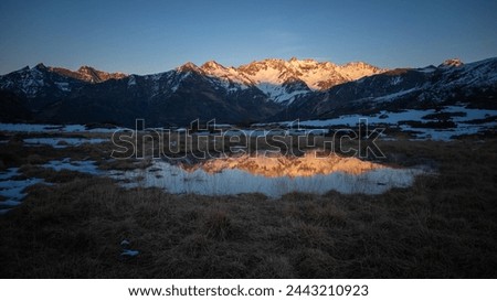 Sunset over the Pyrenees mountains with the reflection of the peaks in the water of the lake