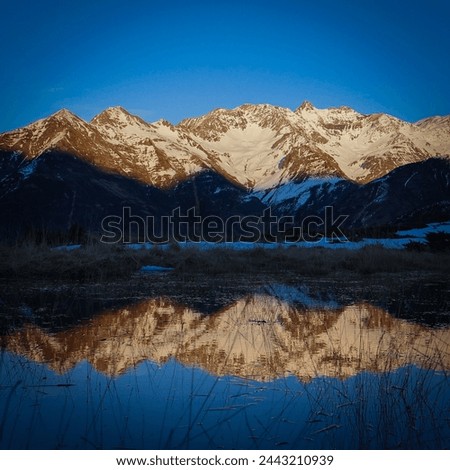 Sunset over the Pyrenees mountains with the reflection of the peaks in the water of the lake