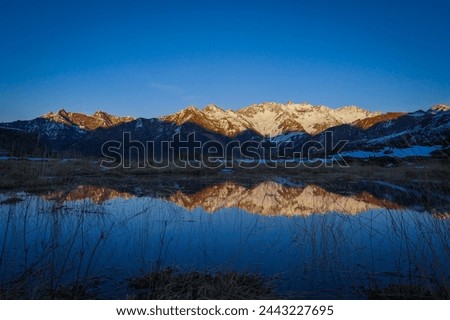Sunset over the Pyrenees mountains with the reflection of the peaks in the water of the lake