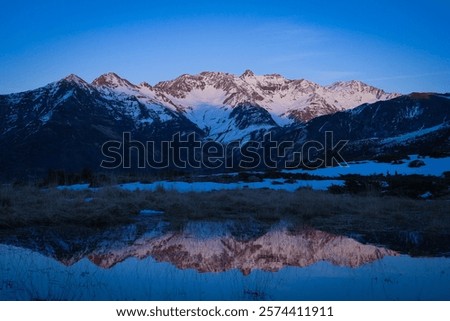 Sunset over the Pyrenees mountains with the reflection of the peaks in the water of the lake