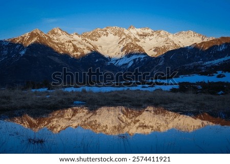 Sunset over the Pyrenees mountains with the reflection of the peaks in the water of the lake