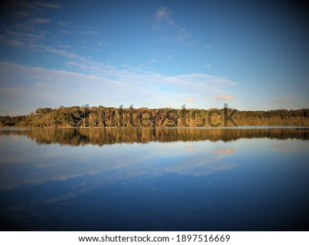 Sunset over Queen Lake, Laurieton, NSW, eucalyptus trees and clouds reflecting off glassy water surface