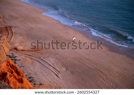 Sunset Over the Red Sandy Cliffs and Calm Waters of Falesia Beach, Portugal