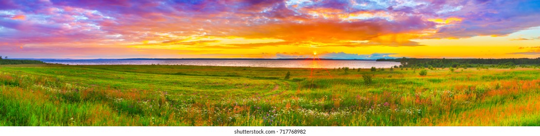 Sunset over the river Kama. Flowers meadow on the foreground. Panorama