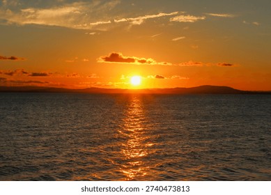 Sunset over a river. Sky with clouds and bluish and orange hues.