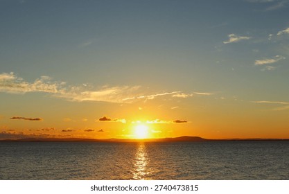Sunset over a river. Sky with clouds and bluish and orange hues.