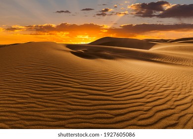 Sunset over the sand dunes in the desert. Arid landscape of the Sahara desert - Shutterstock ID 1927605086