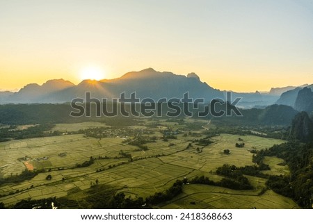 Sunset over a scenic landscape with mountains and fields