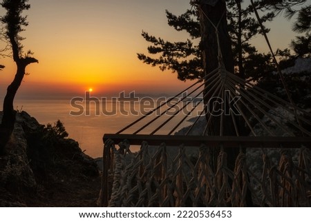 Sunset over the sea horizon. man relaxes in a hammpck by the sea Turket