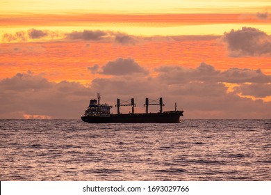 Sunset Over The Sea. A Naval Ship On The Horizon. Oil Tanker Ship At Sea On A Background Of Sunset Sky