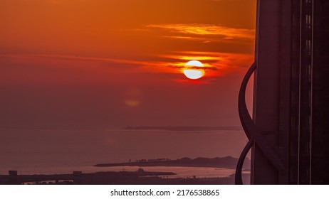 Sunset Over Sea Near Dubai Water Canal With Orange Sky Aerial Timelapse. View From Above Behind Skyscraper