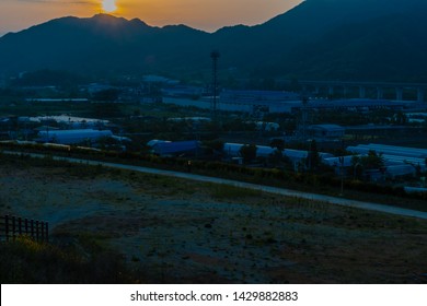 Sunset Over Small Rural Industrial Park In Mountain Valley. 