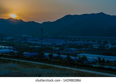 Sunset Over Small Rural Industrial Park In Mountain Valley. 