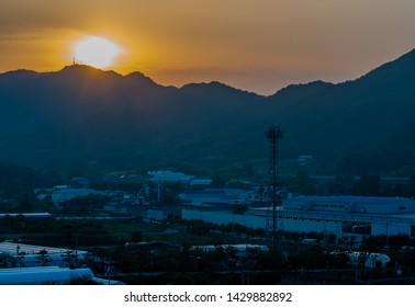 Sunset Over Small Rural Industrial Park In Mountain Valley. 