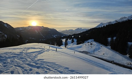 Sunset over snowy alpine landscape in the Swiss mountains. Golden light, deep valleys, and serene winter scenery create a perfect travel and nature background.
