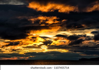 Sunset over stormy clouds across the water reflecting dark and looming dramatic sky moody - Shutterstock ID 1107455714