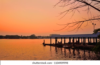 Sunset over Vembanad Lake in Marine Drive, Kochi with silhouette of boat jetty and trees in the background..