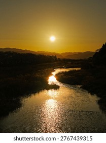 Sunset over winding river with reflection and mountains