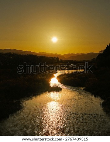 Sunset over winding river with reflection and mountains