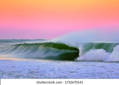 Sunset Perfection, an image of a wave breaking during sunset in Japan the wave is a perfect right hand barrel wave and the sunset is after a typhoon with stunning pinks and purples and hints of orange