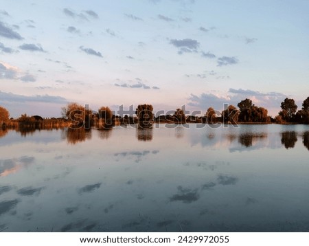 Sunset at the phishing lake. Horizon mirror reflection in the lake.clouds and trees reflection in lake