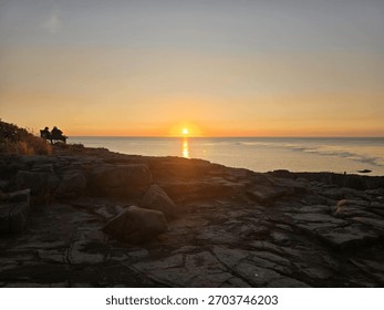 Sunset at Point Prim in Digby, Nova Scotia, overlooking the Bay of Fundy at low tide. Rugged rocky shoreline, golden sky, and peaceful Atlantic Canada coastal scenery.