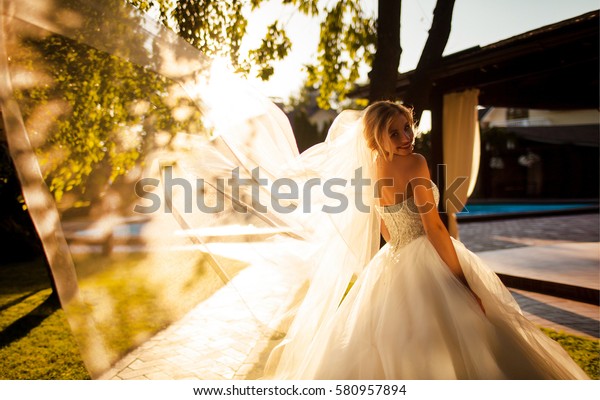 Sunset portrait of smiling bride. happy gorgeous\
bride smiling in the evening warm sunlight. sensual emotional\
moment of luxury wedding, young bride in amazing sunset. happy\
bride at sunset.