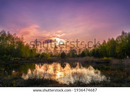Sunset in purple mood on a lake with reflections on the water