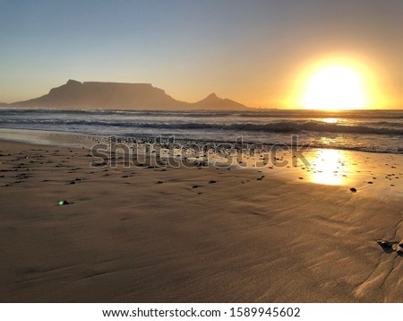 Sunset rays next to Table Mountain and Lionshead from  the beach on Sunsetbeach in Cape Town, South Africa