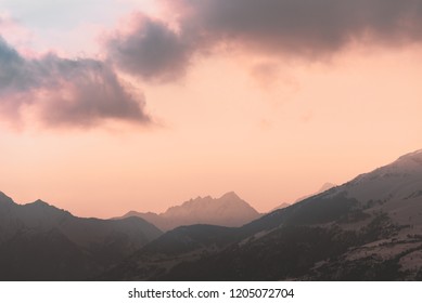 Sunset with red cloud over distant mountain peaks, blue, yellow, orange, mellow