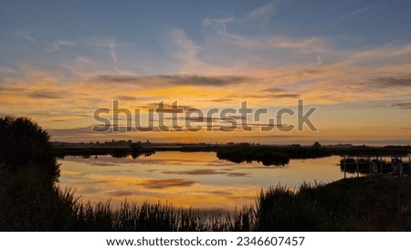 Sunset with red colored sky, mirrored in water; Smallingerland, Friesland, Netherlands