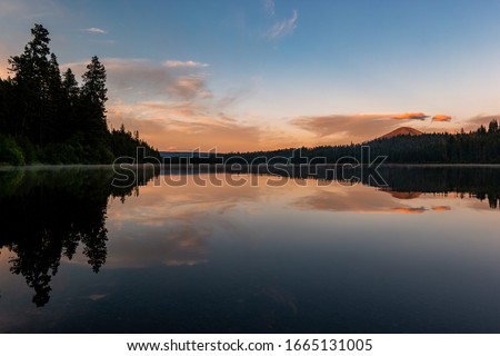 Sunset reflection on a lake in a forest in the Cascade Mountains in Central Oregon.