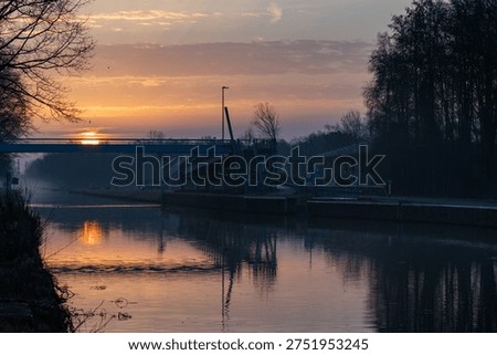 Sunset reflection over construction site in Belgian Campine region with golden hour lighting and bridge development