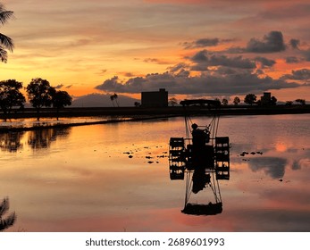 Sunset reflection with a paddy field tractor. The orange sky and calm water create a peaceful rural landscape, symbolizing traditional agriculture and countryside life in Perlis, Malaysia