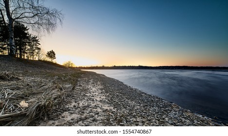 Sunset at the river coast. Smooth water at river