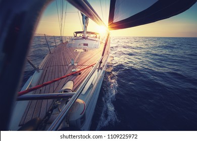 Sonnenuntergang auf dem Segelboot-Deck während der Fahrt / Segeln auf geöffnetem Meer. Yacht mit vollen Segel am Ende des windigen Tages. Segelthema - Hintergrund. Yachting-Hintergrund-Design.